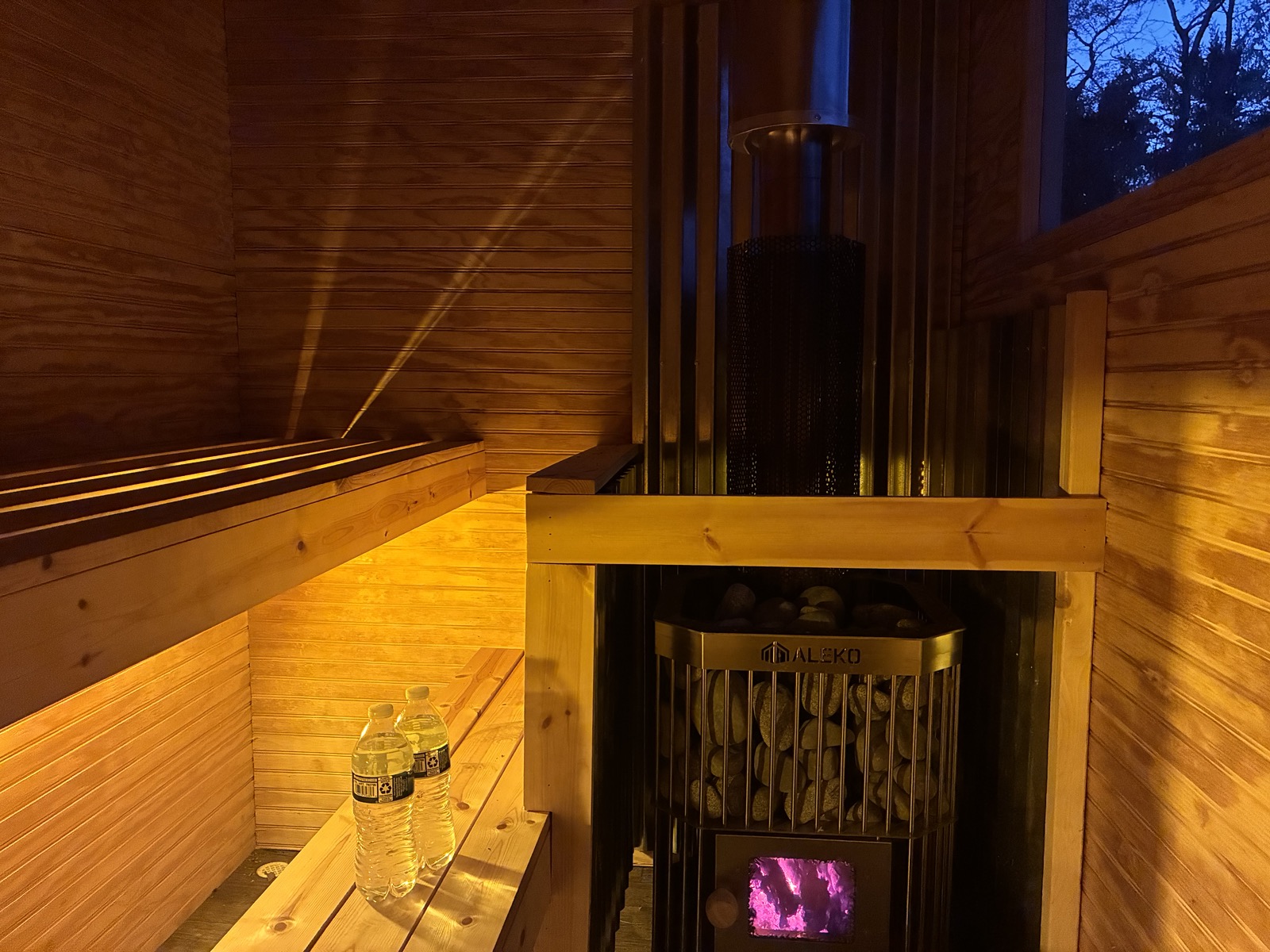 Pine sauna benches beside the wood-fired stove with glowing coals